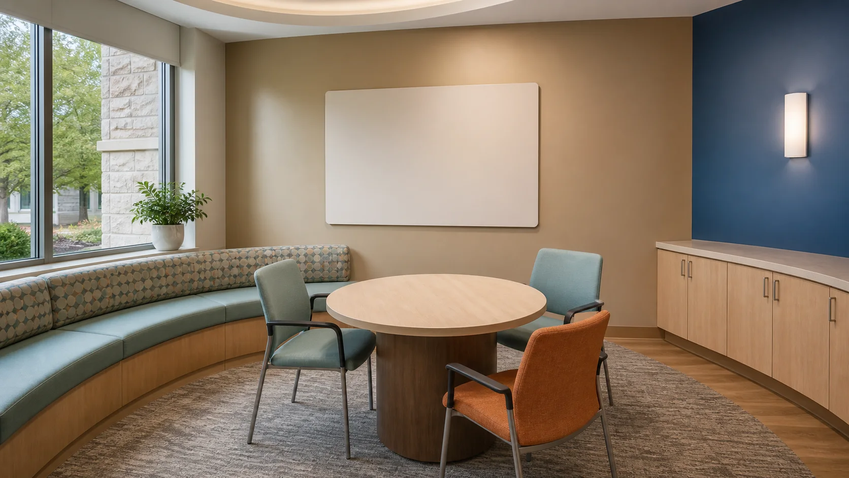 A calm outpatient education room with a rounded shared table and daylight.